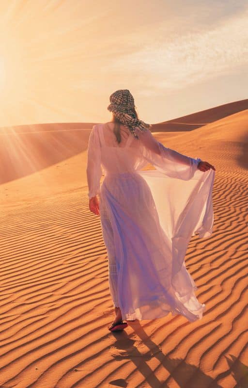 single women in the desert walking on the sand dunes